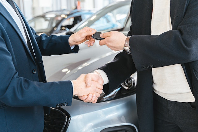 people exchanging car keys and shaking hands