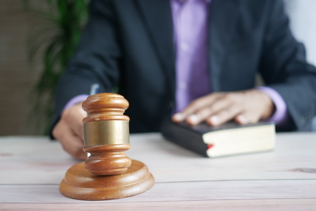 man with hand on book hitting gavel